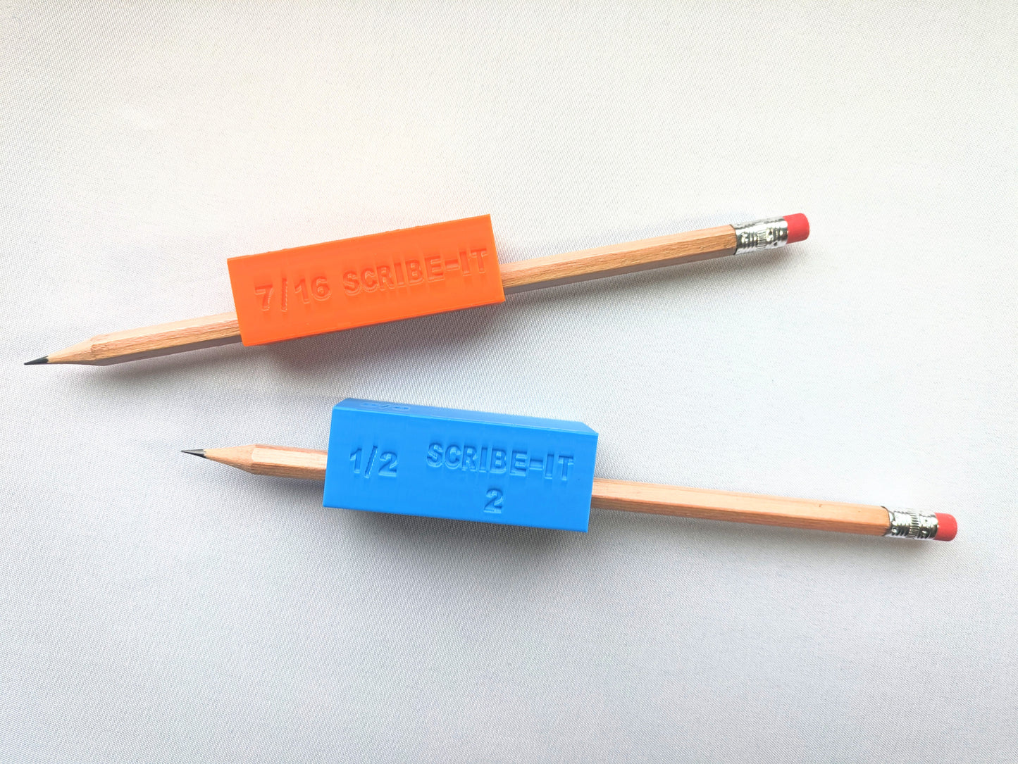 Orange and blue carpentry Scribe-It scribe tools with pencils inside and a white background.